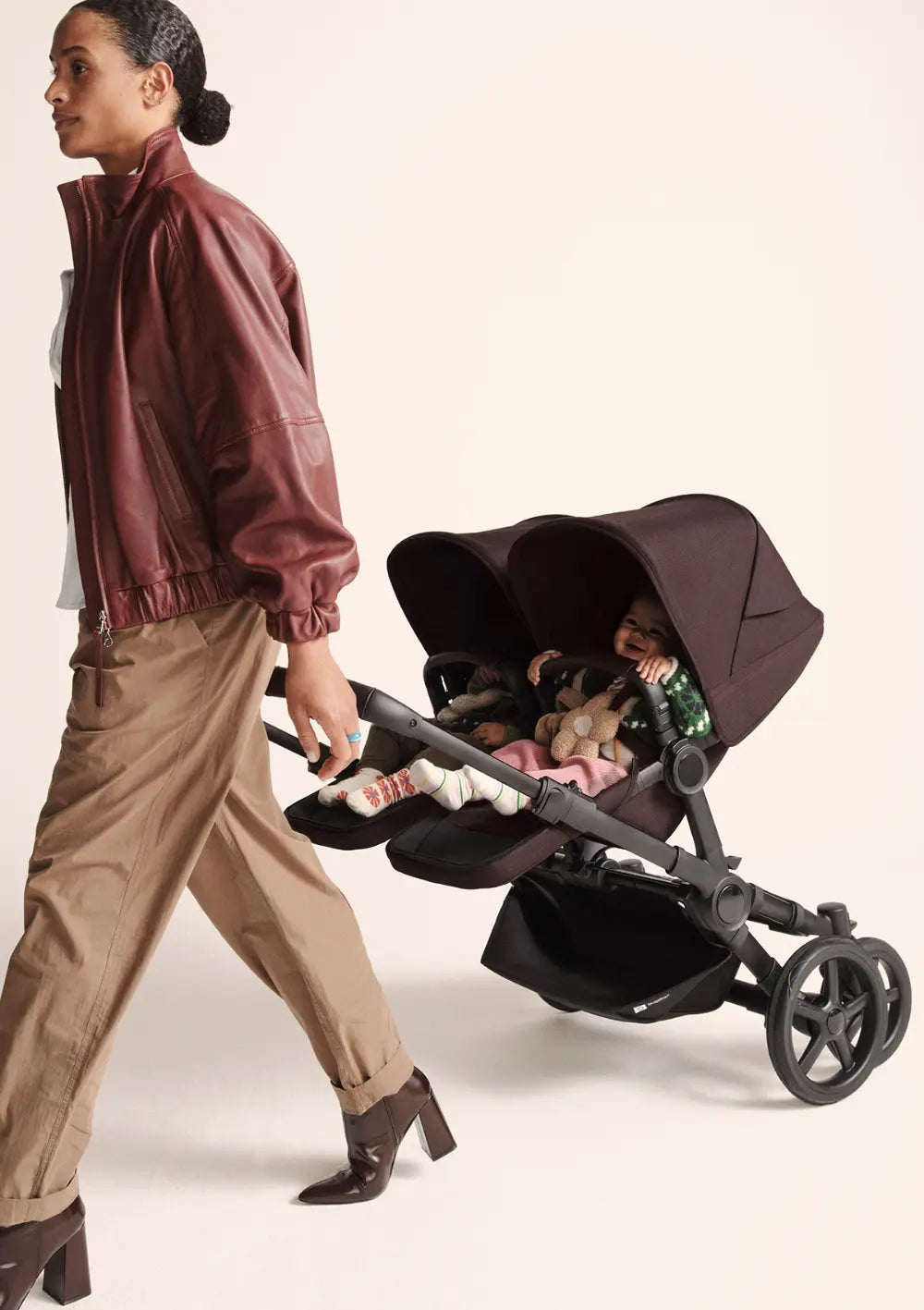 Frau zieht Bugaboo Zwillingskinderwagen 'Donkey 6 Twin' Cocoa Brown hinter sich her