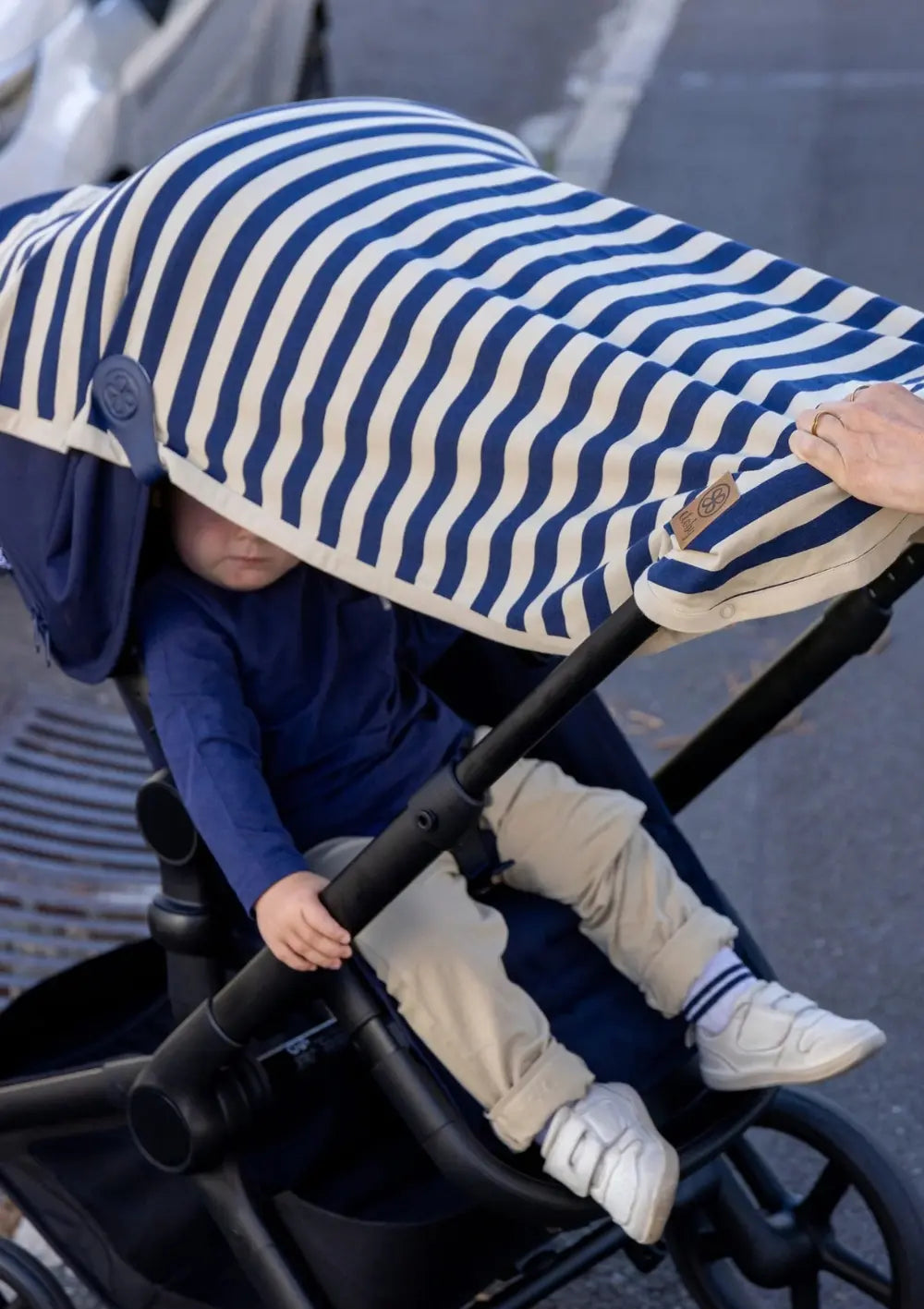 Cloby Multifunktionale UV-Decke UPF 50+ Navy Stripe mit 2er-Set Magnet-Clips Leder Navy Blue am Kinderwagen befestigt – Junge sitzt sonnengeschützt im Kinderwagen