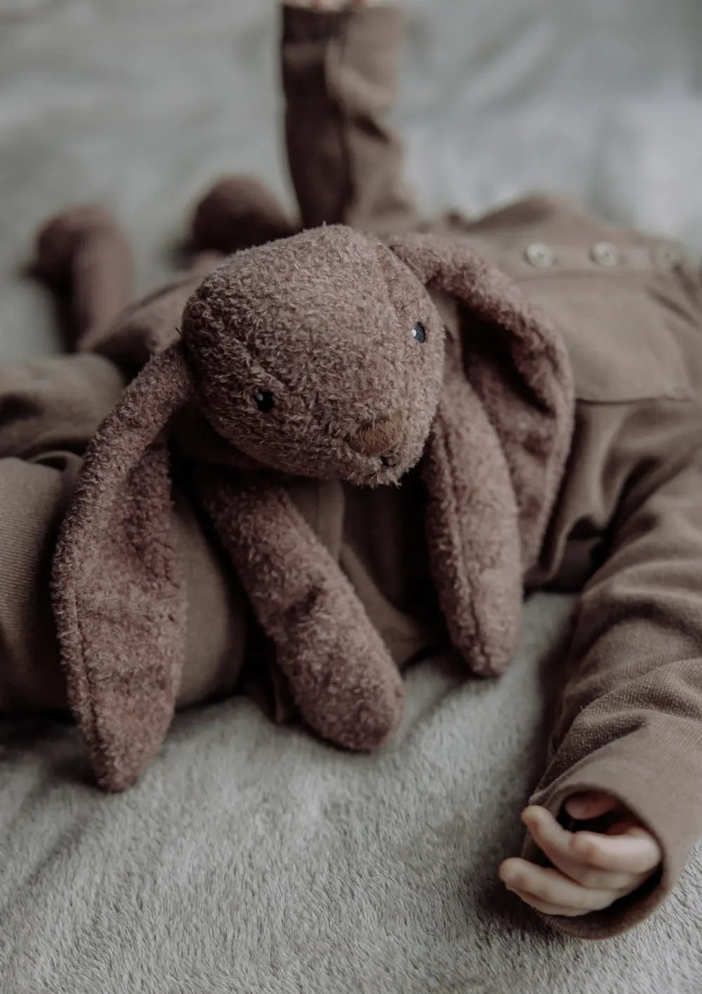 flow AMSTERDAM Wärmekissen Hase 'Milo' chocolate liegt auf Babybauch