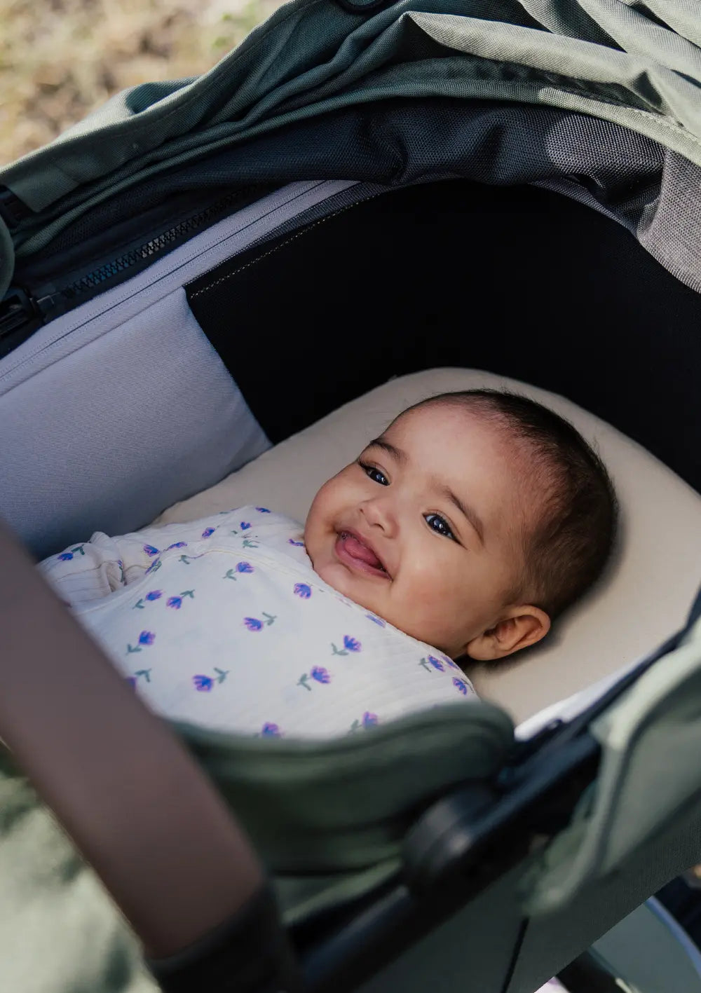 Baby liegt in der Joolz Babywanne 'Geo5' Forest Green und lächelt