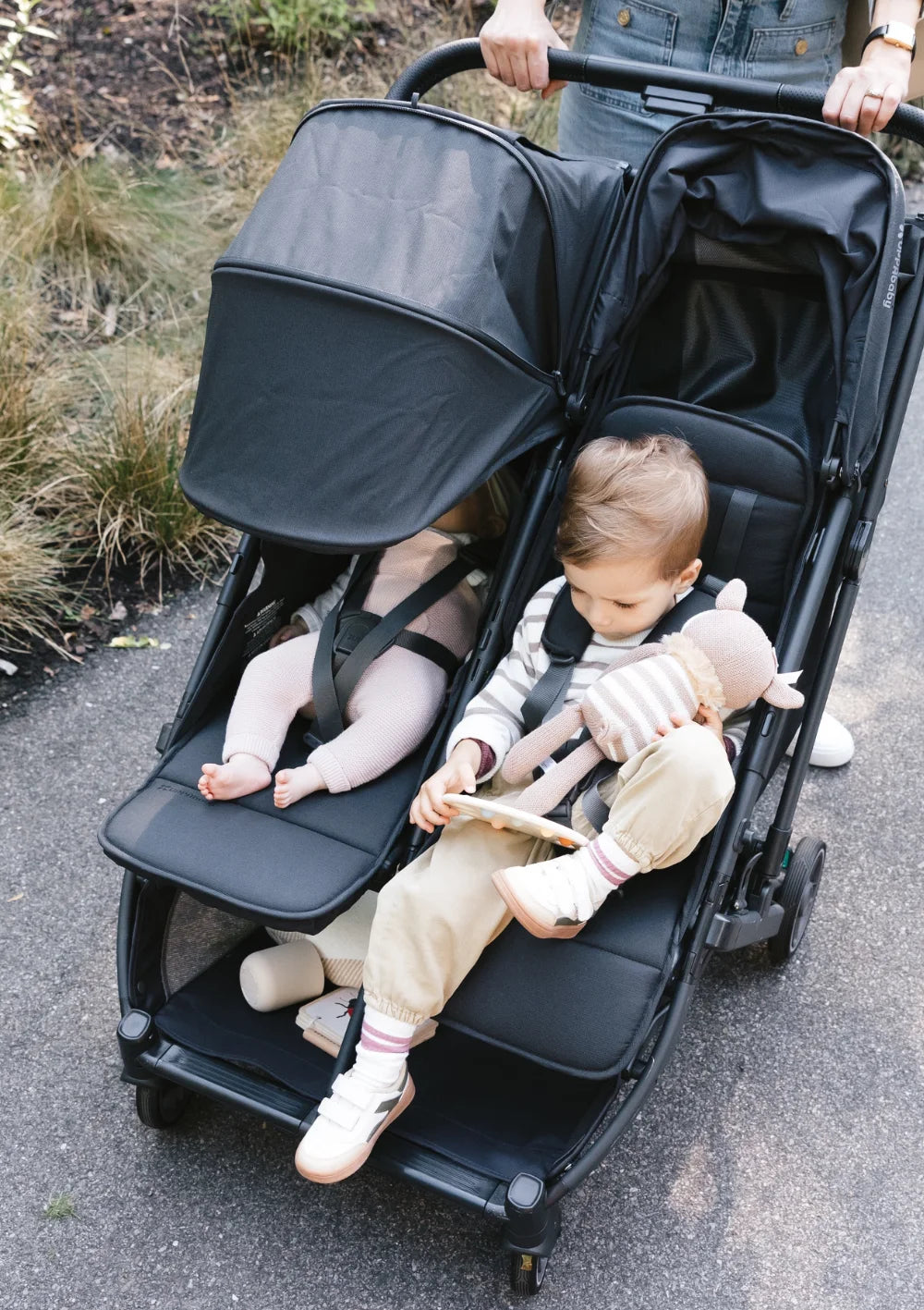 Komfort auf jedem Weg: Vogelperspektive auf zwei Kleinkinder, die im UPPAbaby Geschwisterbuggy Minu Duo Jake liegen und sitzen.