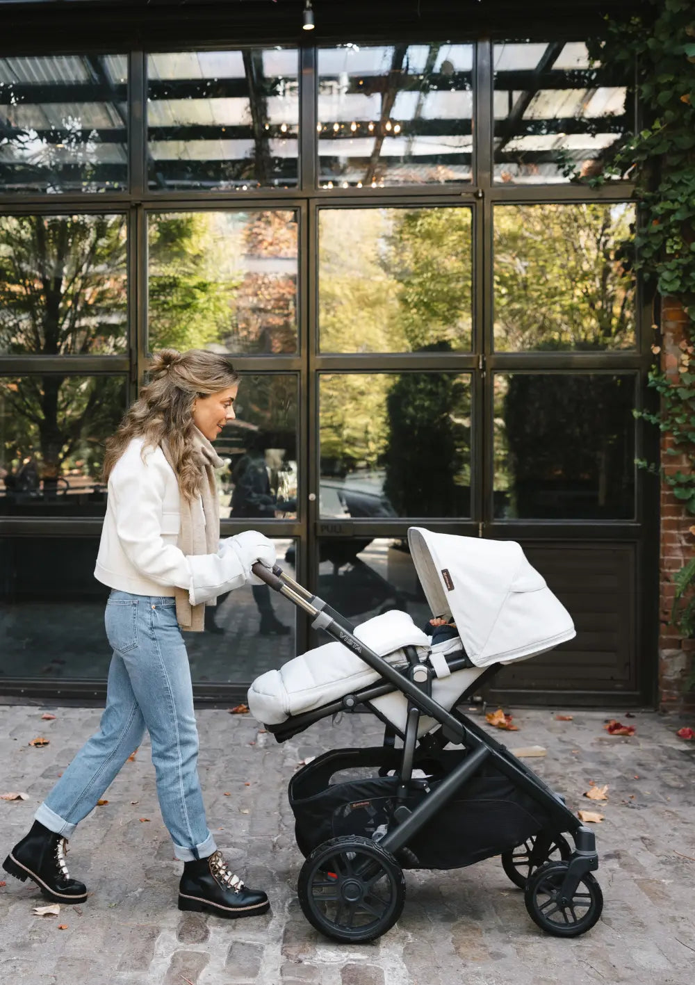 Frau schiebt UPPAbaby Kinderwagen 'Vista V3' Savannah mit Sportsitz und farblich abgestimmten Fußsack