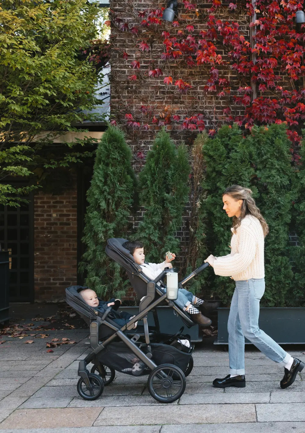 Eine Frau spaziert mit zwei Kindern im Kinderwagen-Set UPPAbaby 'Vista 3' Jake mit zwei Sportsitzen durch die Stadt