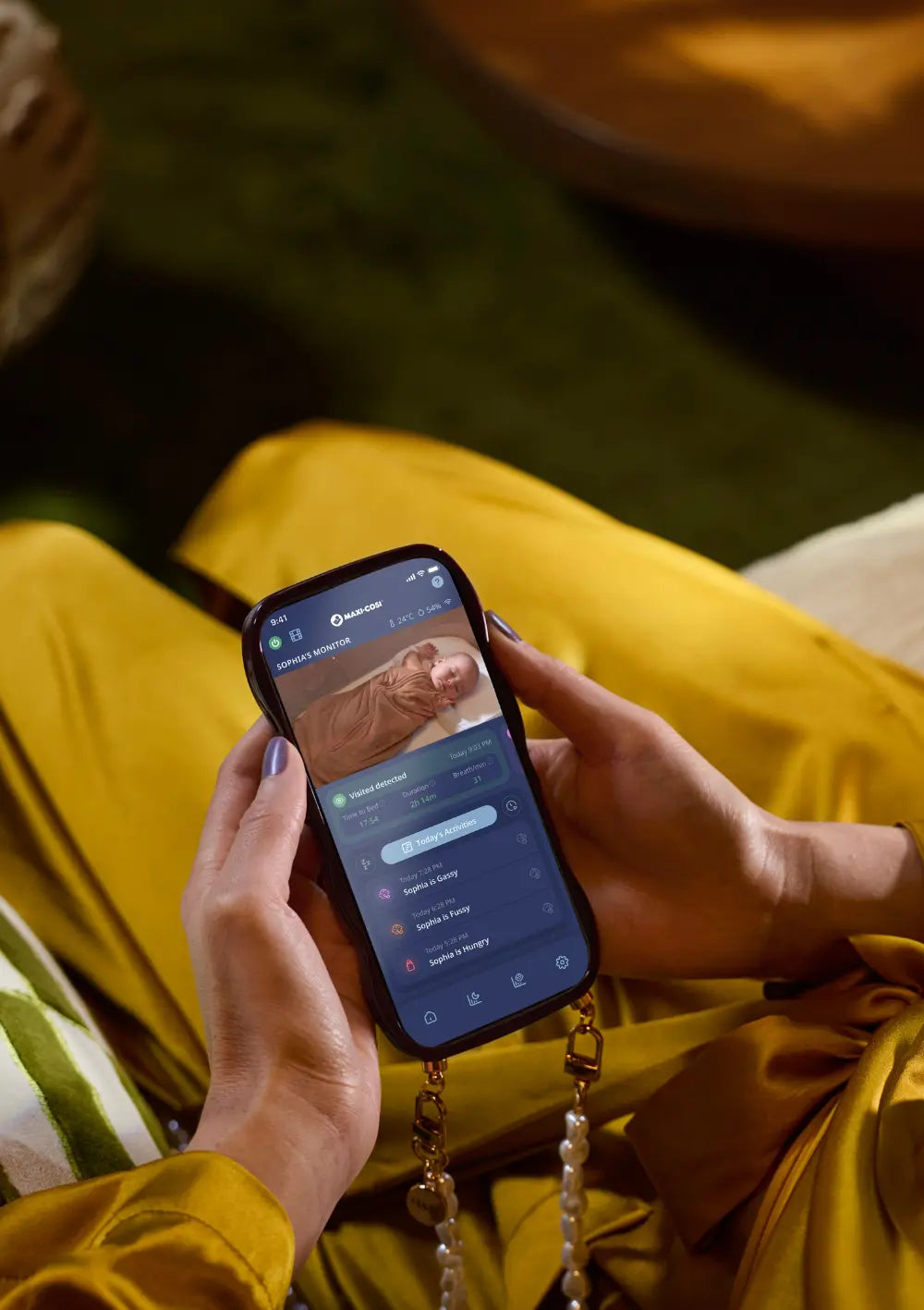 Steuerung via Smartphone: Blick auf die Maxi-Cosi App auf einem Smartphone, die das Live-Video und Aktivitätsdaten des Maxi-Cosi Smart Baby Monitor Connected Home See 2 Pro Elegance Beige anzeigt.