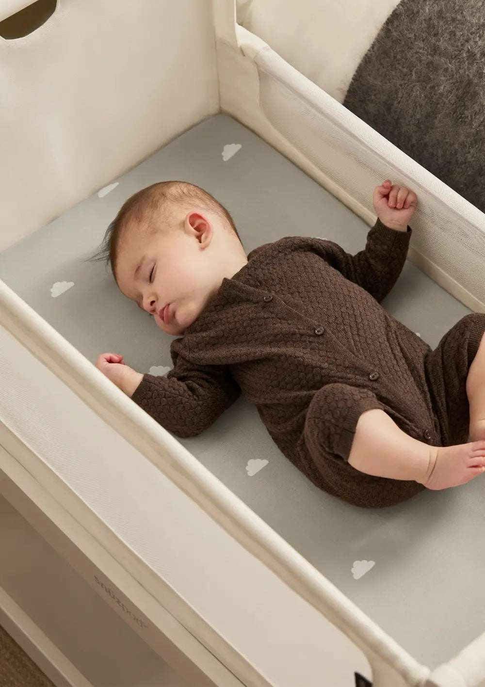 Draufsicht auf ein schlafendes Baby im weißen Snüz Beistellbett SnüzPod 5; weiche Matratze mit Wolkenmuster und schützende Stoffwände sorgen für geborgenen Schlaf.