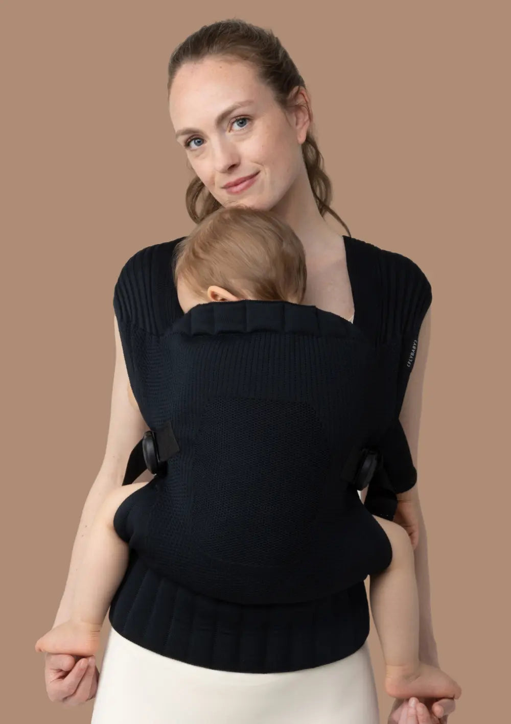 Frau trägt ihr Kleinkind in der Flybaby Kleinkindtrage Black vor dem Bauch.