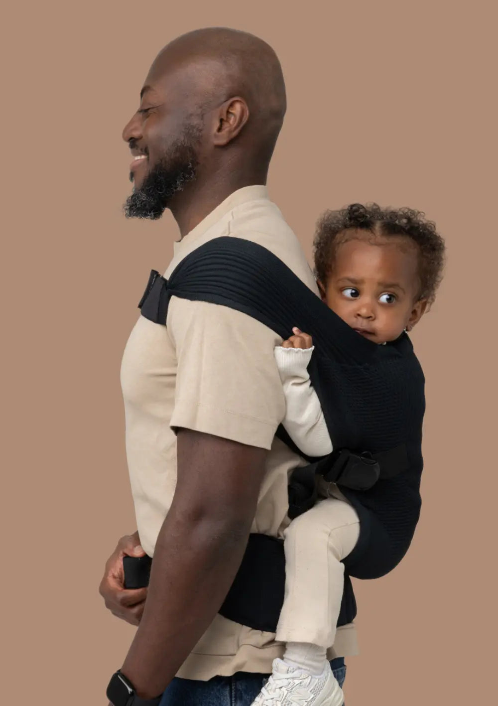 Mann trägt sein Kleinkind in der Flybaby Kleinkindtrage Black sicher auf dem Rücken.