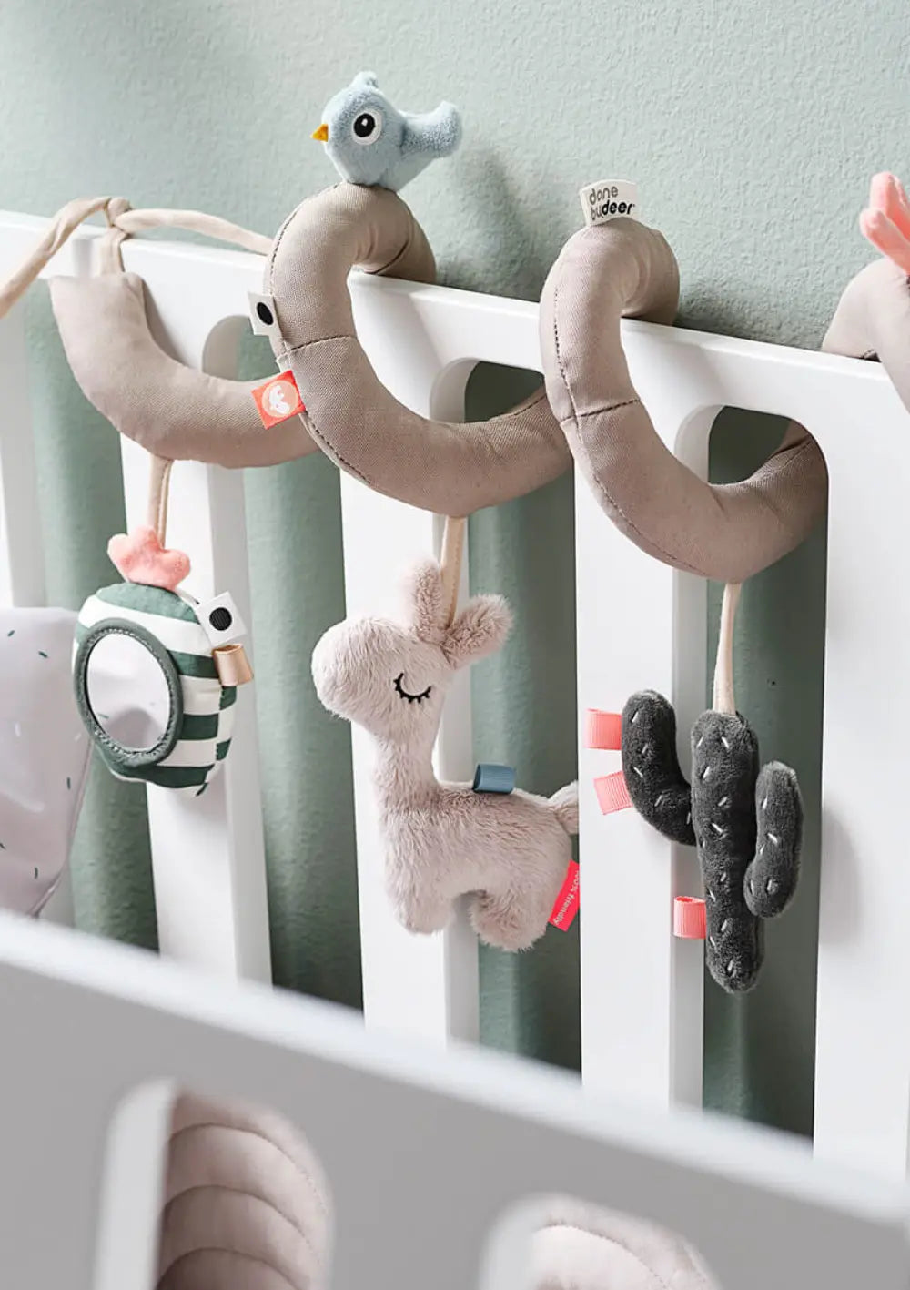 Done by Deer Activity Spirale 'Lalee' sand, befestigt am Gitter des Kinderbetts