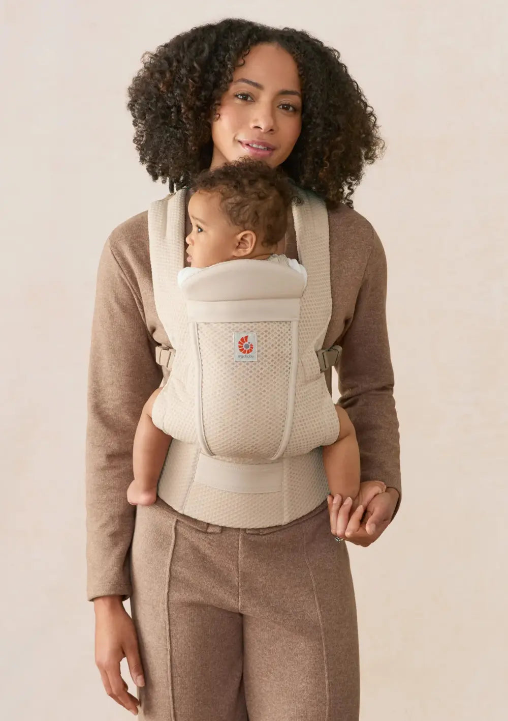 Frau trägt ihr Baby in der Ergobaby Babytrage 'Omni Lite' Mesh Natural Beige