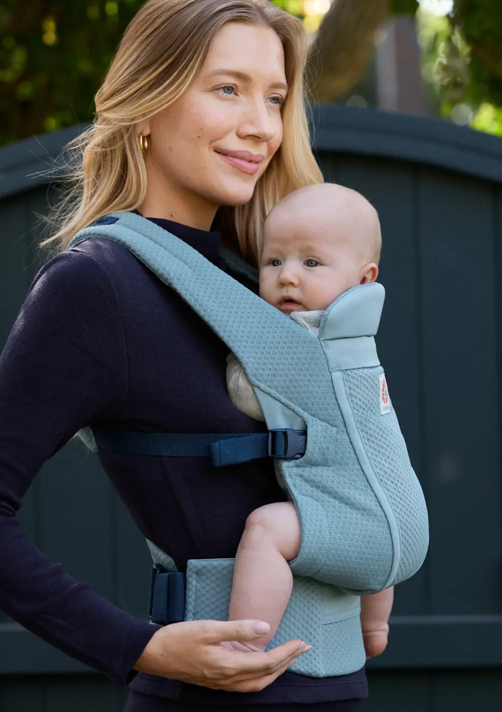 Frau trägt Baby in der Ergobaby Babytrage 'Omni Lite' Mesh Slate Blue