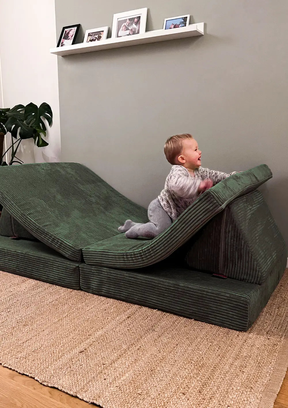 Baby krabbelt auf dem Funzy Spielsofa Cord Tannen Grün