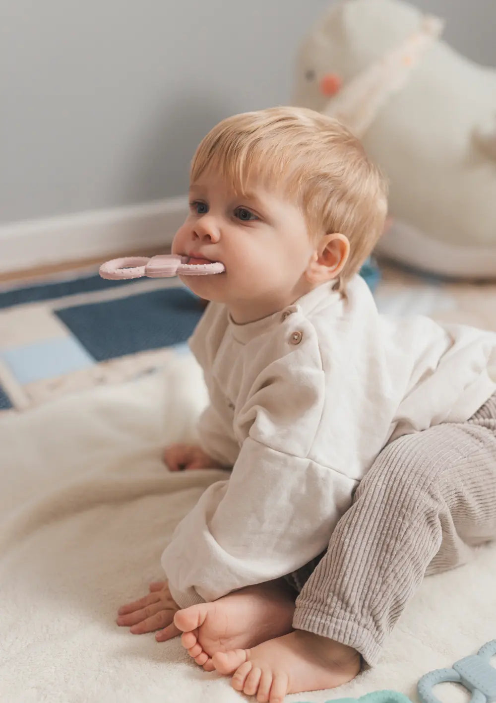 mimiloo Silikon Lern- und Beißring Rose – Kleinkind mit dem Beißring im Mund im Kinderzimmer.