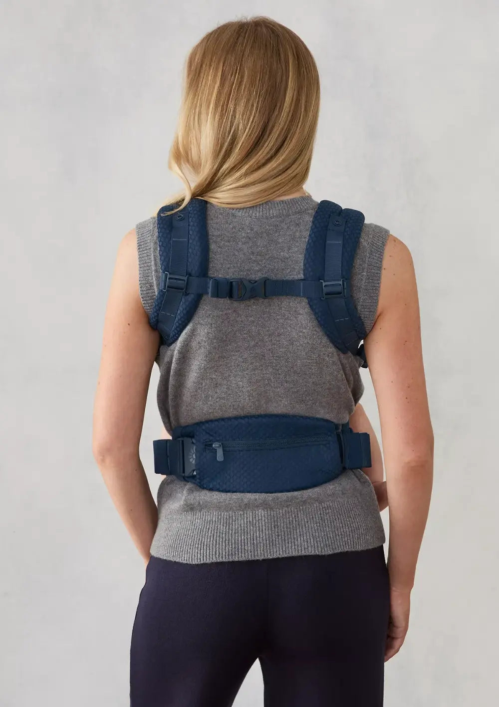 Frau trägt ihr Baby in der Ergobaby Babytrage 'Omni Deluxe' Mesh Midnight Blue in der Fronttrageweise (Rückansicht)