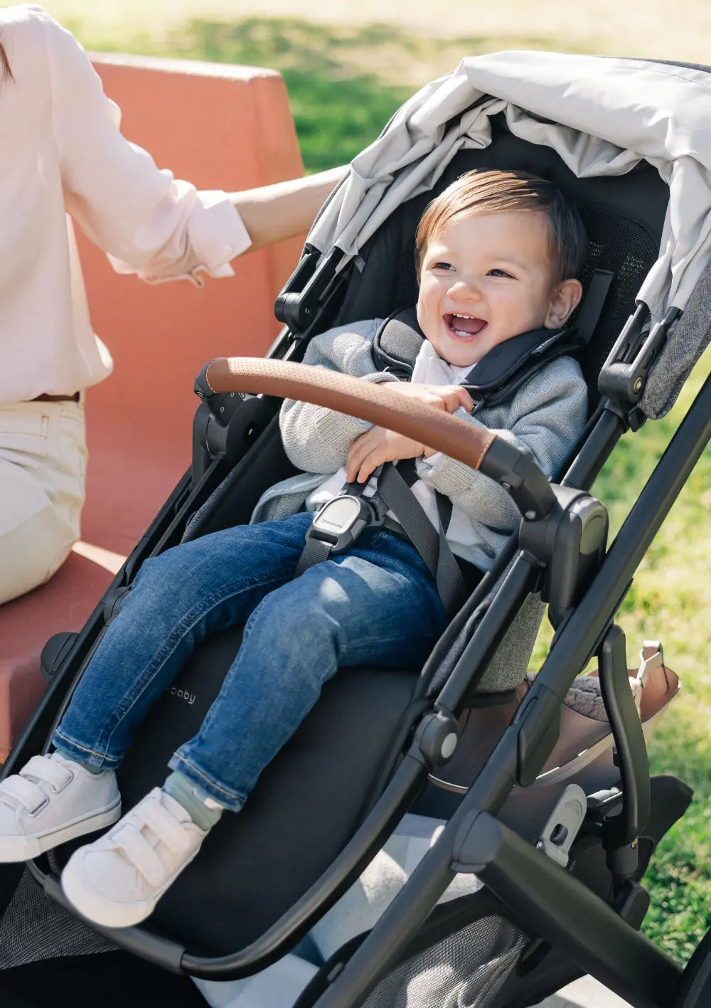 Ein lachendes Kind sitz im Sportsitz des UPPAbaby Kinderwagens 'Vista V3' Greyson