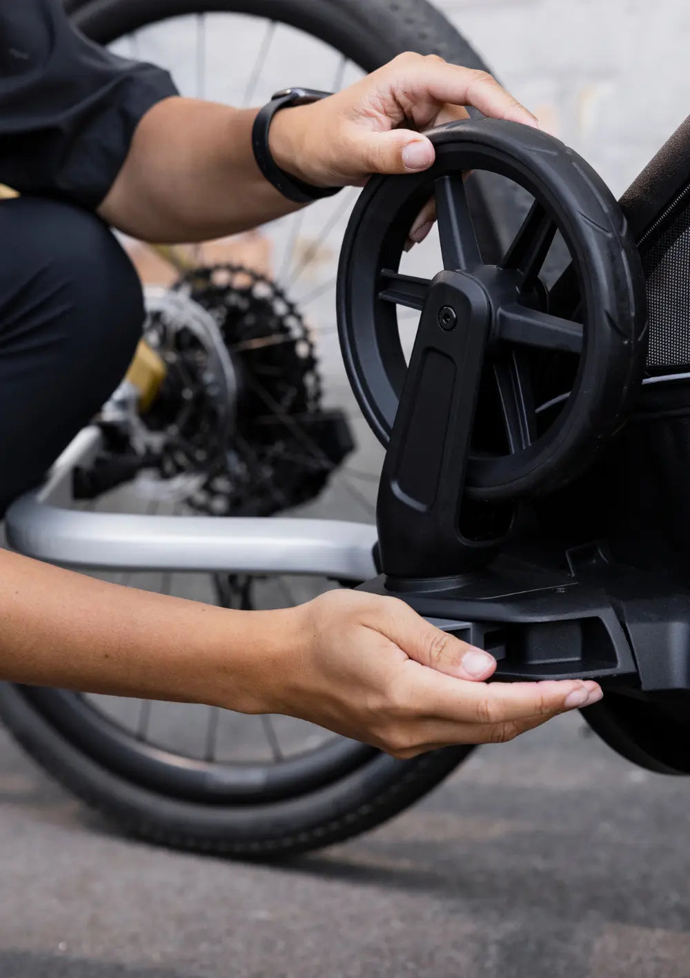 Detailansicht der einfachen Montage des Vorderrads am Thule Multisport-Fahrradanhänger Chariot Sport 2 Single Black für den Wechsel vom Buggy- in den Fahrradmodus.
