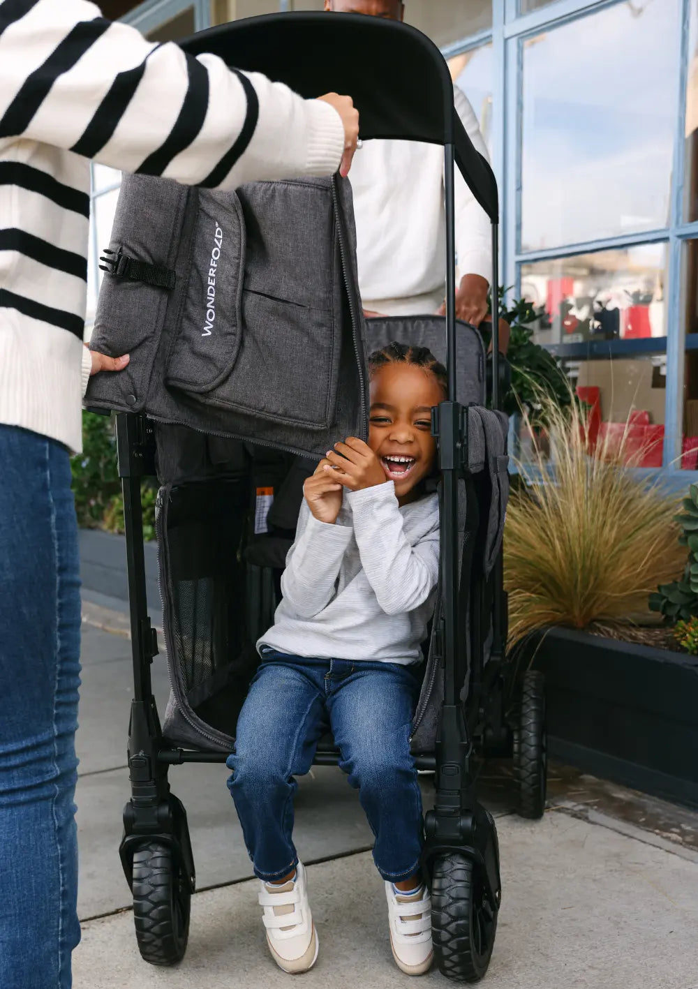 Ein fröhlich lachendes Kind sitzt im WonderFold W2 Luxe Pro Kinderwagen 2-Sitzer.
