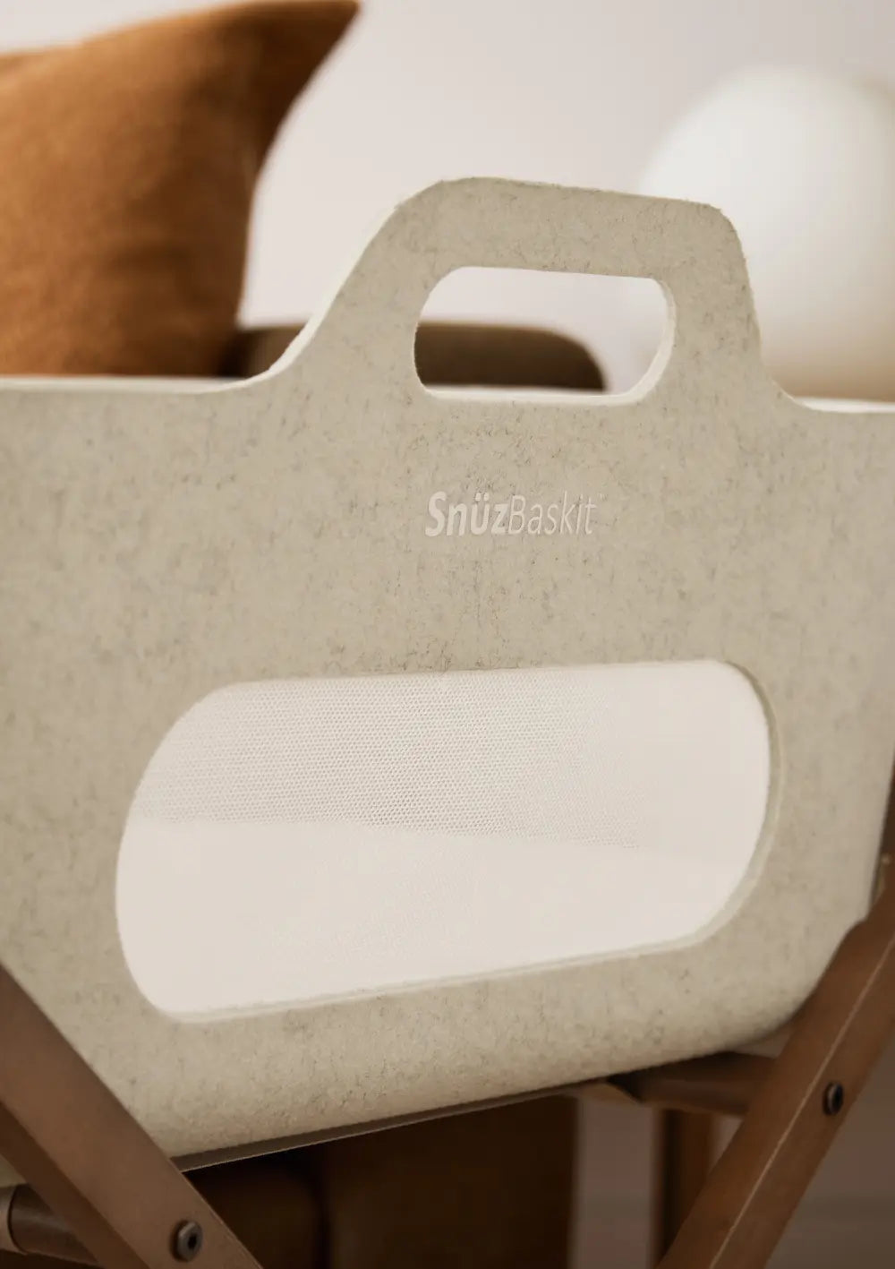 Detailansicht des Snüz Moseskorb inkl. Ständer SnüzBaskit Barley-Walnuss; Fokus auf den integrierten Tragegriff, das Mesh-Gewebe und das dezente SnüzBaskit-Logo.