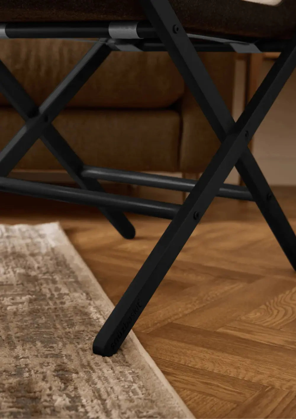 Detailansicht des mattschwarzen X-Gestells vom Snüz Moseskorb inkl. Ständer SnüzBaskit Graphite auf Parkettboden und einem Teppich.