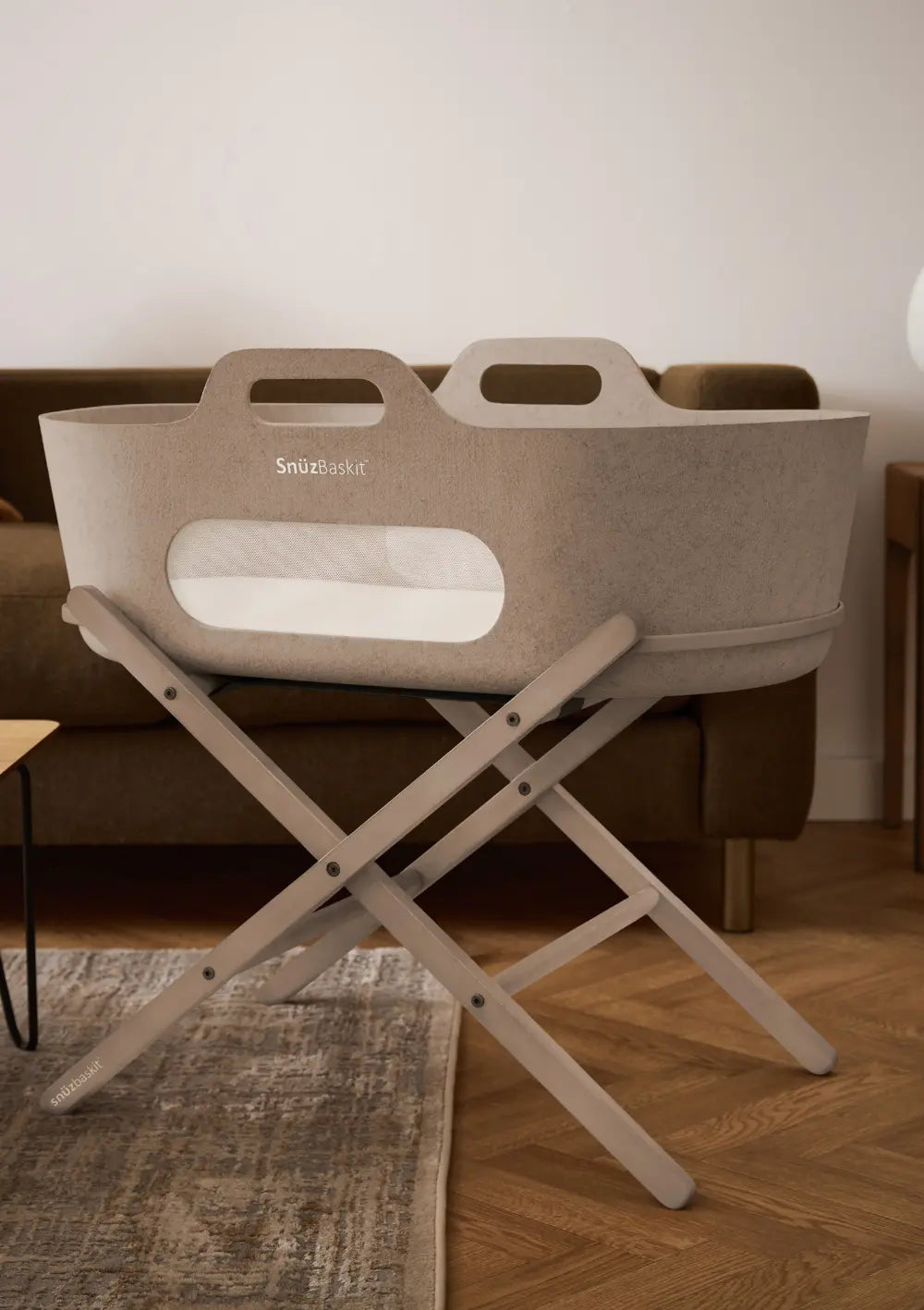 Der moccafarbene Snüz Moseskorb inkl. Ständer SnüzBaskit Mocha auf seinem stabilen, kreuzförmigen Holzständer; elegante Babywiege für ein gemütliches Zuhause.