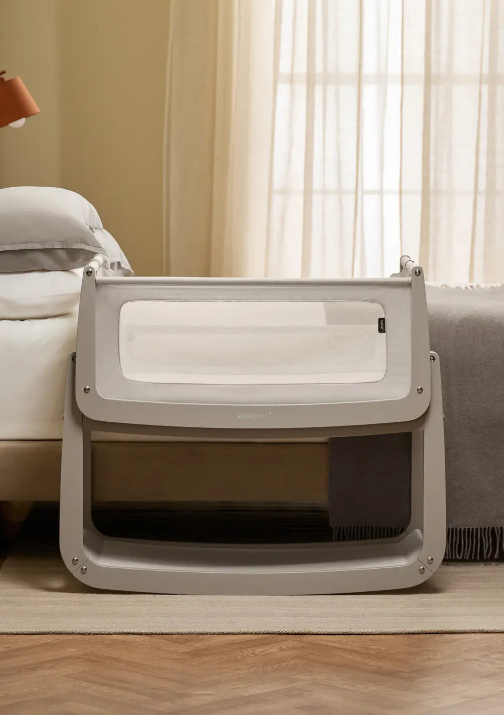 Das Snüz Beistellbett SnüzPod 5 Pebble mit grauem Holzgestell steht passgenau und sicher direkt neben der Matratze des Elternbettes.
