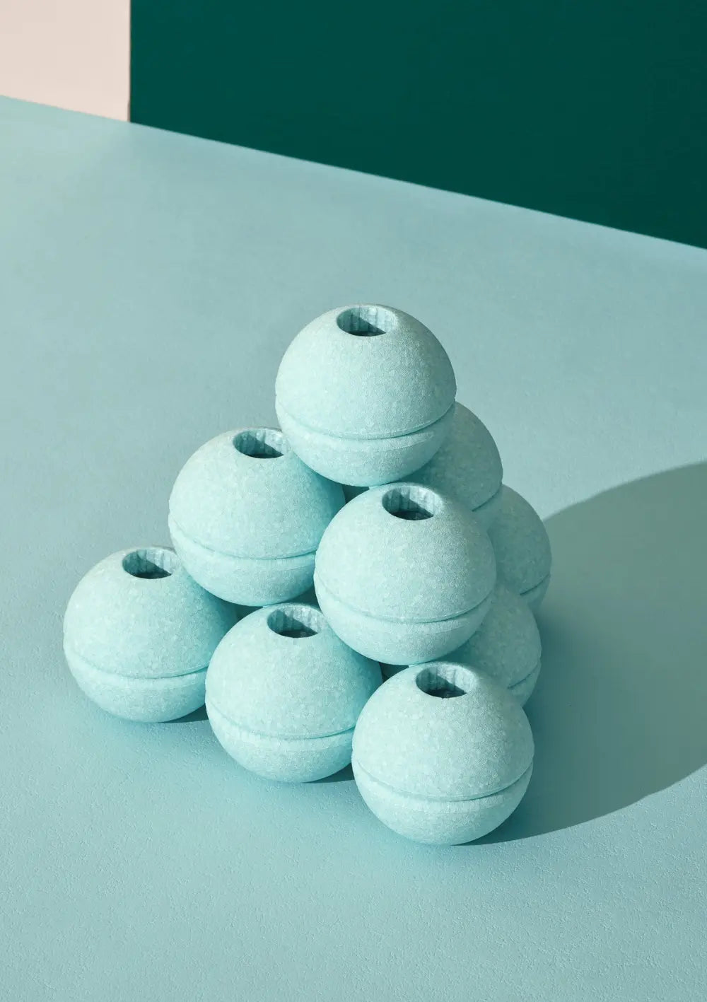 Mehrere mintgrüne Spielbälle aus dem MODU 3er-Set Schaumstoffbälle Mint sind zu einer kleinen Pyramide aufgestapelt und zeigen die charakteristischen runden Öffnungen für die MODU-Verbindungsstifte.