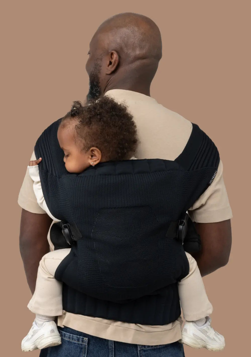 Mann trägt sein Kleinkind in der Flybaby Kleinkindtrage Black sicher auf dem Rücken.