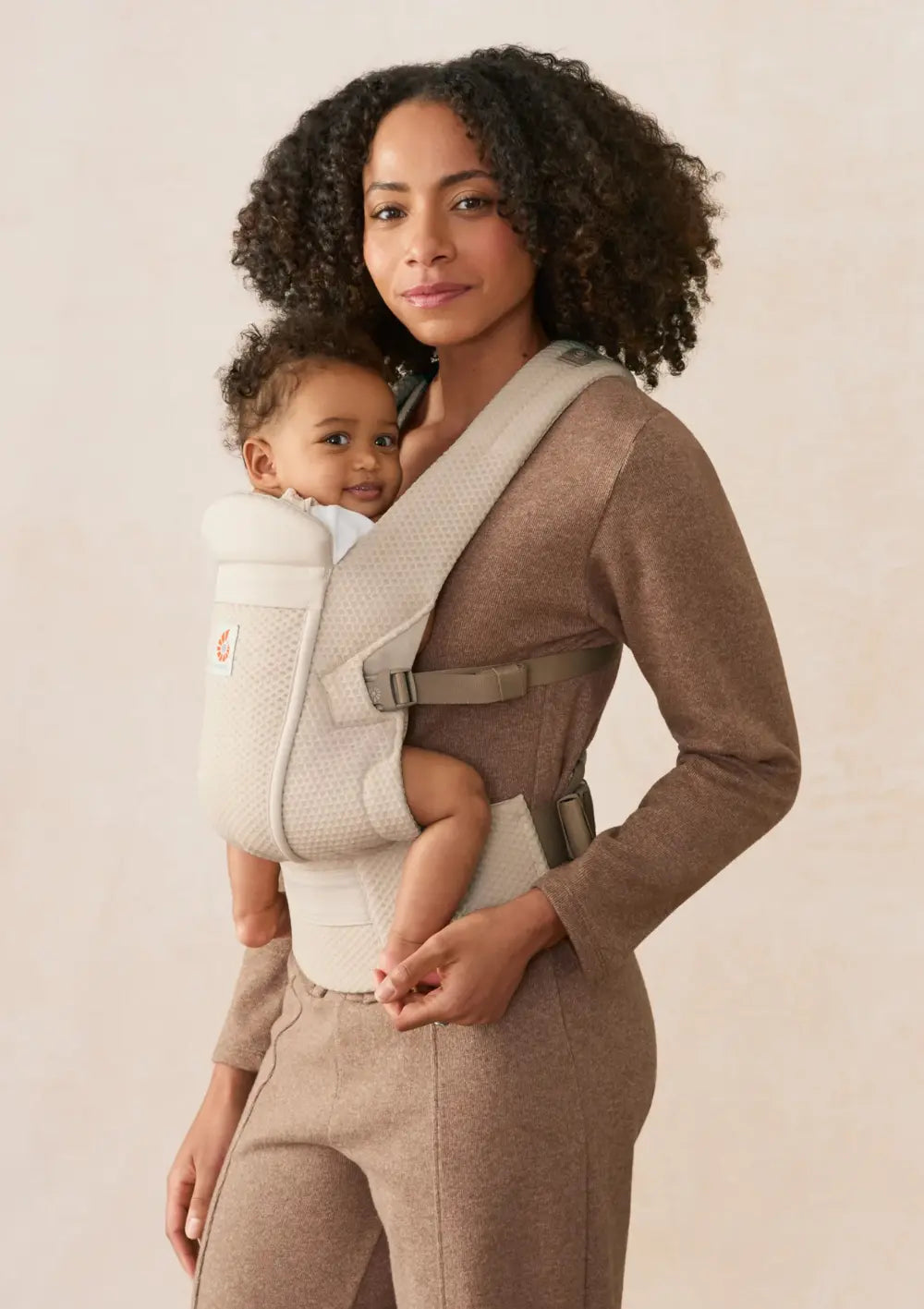Frau trägt ihr Baby in der Ergobaby Babytrage 'Omni Lite' Mesh Natural Beige