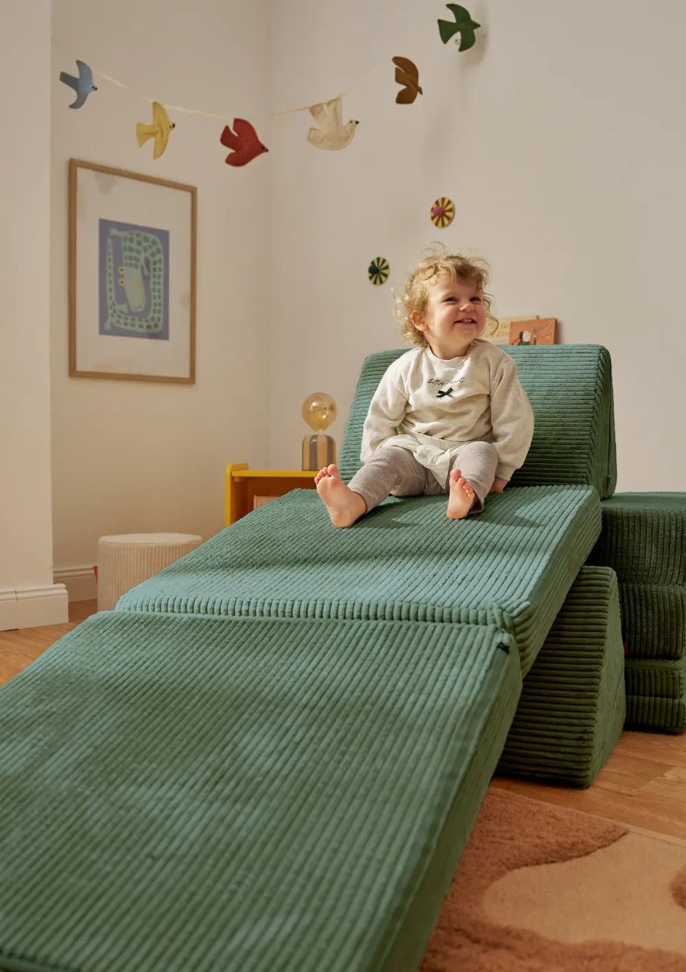 Kind nutzt das Funzy Spielsofa Cord Tannen Grün als Spielrutsche im Kinderzimmer