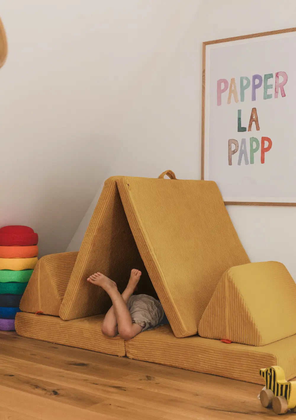Kind liegt in Höhle im Kinderzimmer – gebaut aus dem Funzy Spielsofa Cord Senf Gelb