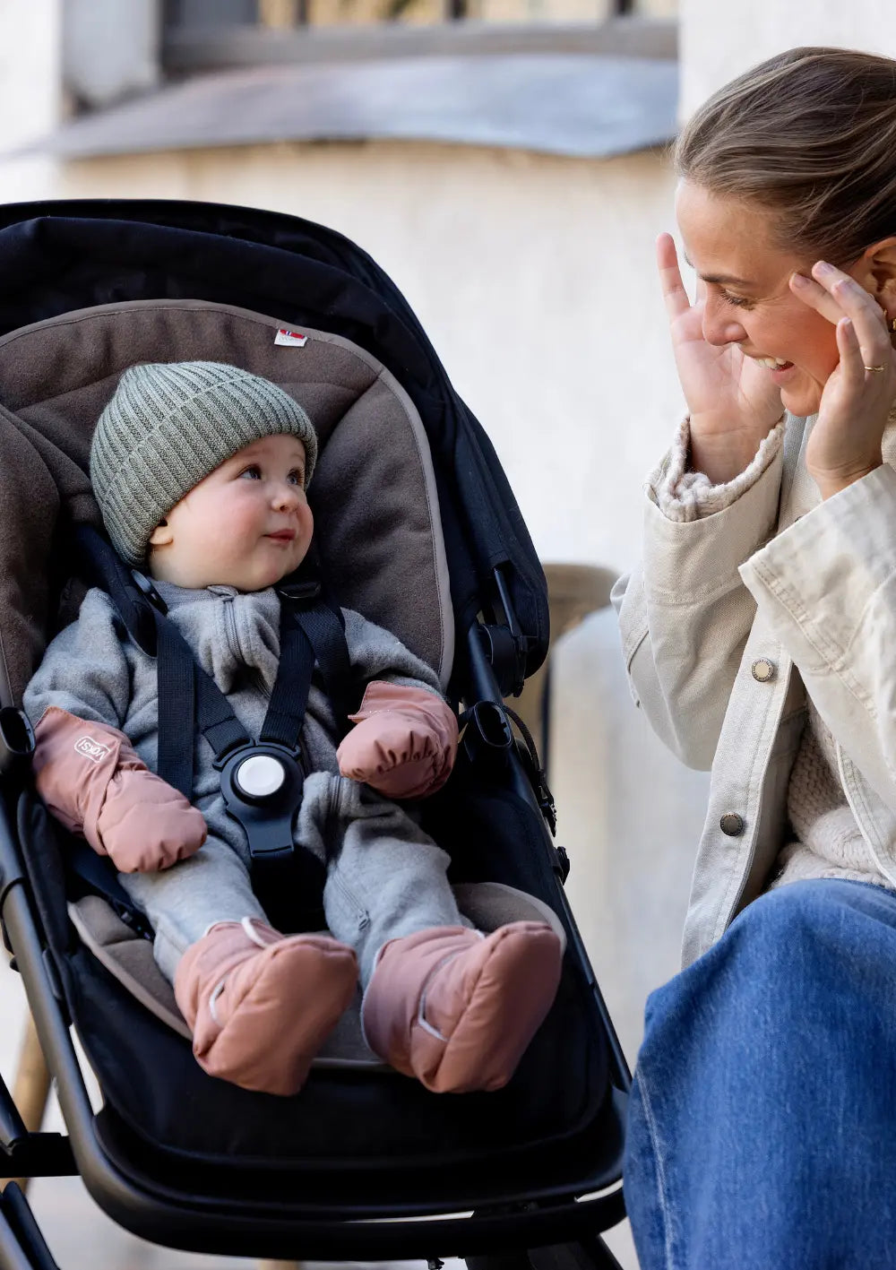 EIn Baby sitzt im Kinderwagen und schaut zu seiner Mama, ausgestattet miit den Voksi Baby Booties Blush Pink